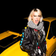 portrait de l'artiste suisse romande Evelinn Trouble devant une voiture jaune
