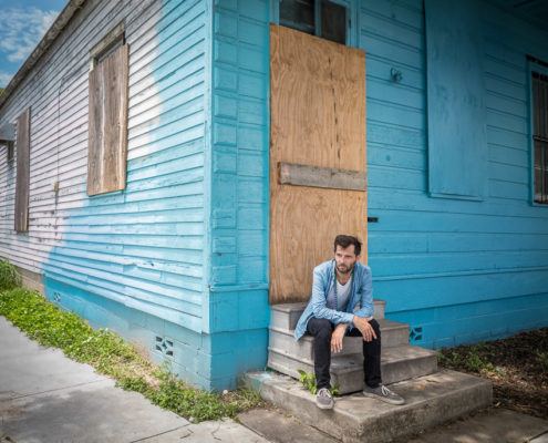 Hugh Coltman devant une maison bleu pour la sortie de son album "Who's Happy ?"
