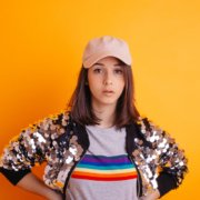 Portrait sur fond orange de la jeune artiste Clarisse Mây pour la sortie de son EP "Panache"
