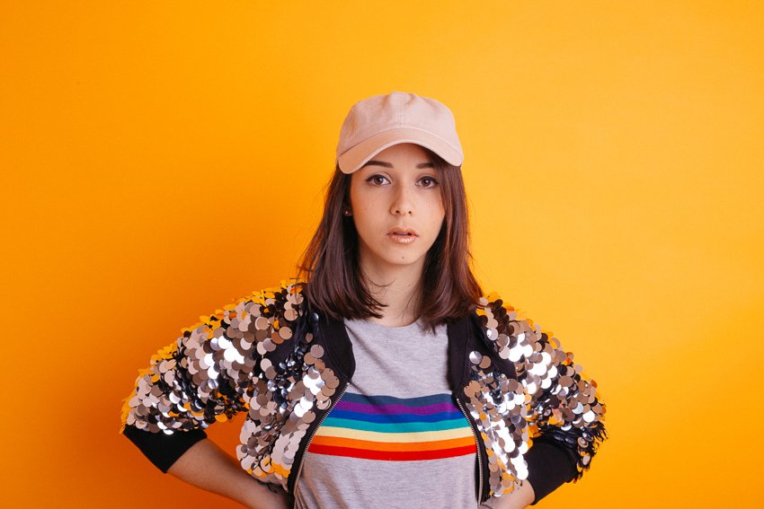 Portrait sur fond orange de la jeune artiste Clarisse Mây pour la sortie de son EP "Panache"