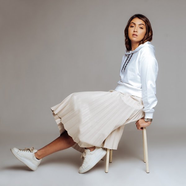 L'artiste féminine Yezza tout en blanc assise sur une chaise pour la promotion de son titre Gare du Nord