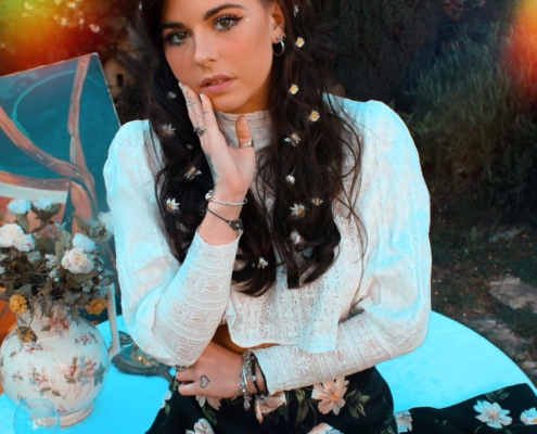 portrait posé de l'artiste MOGGY assise avec jupe à fleur et haut blanc