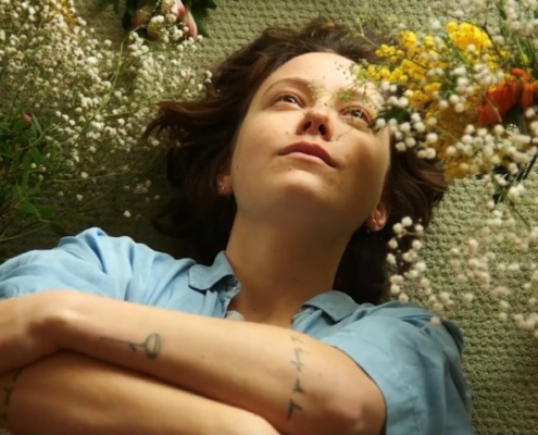 portrait d'une jeune femme couchée dans des fleurs issu du clip "partir" de T O D