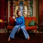 portrait en pied de Tiphanie Doucet assise sur un canapé rouge